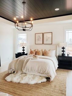 a bedroom with a large bed and chandelier hanging from it's ceiling