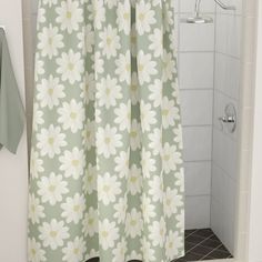 a shower curtain with white daisies on it and a green towel next to it