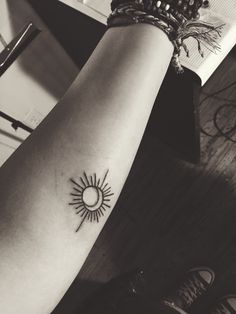 a woman's arm with a small sun tattoo on it