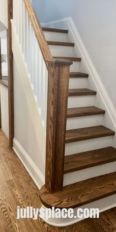 a wooden staircase with white handrails and wood flooring in a home's entryway