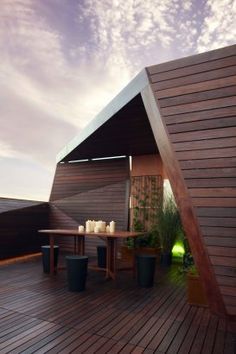 an outdoor dining area on the roof of a building with wooden decking and potted plants