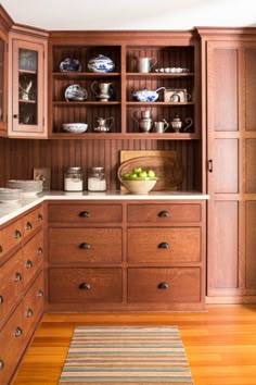 a kitchen with wooden cabinets and white counter tops, along with a striped rug on the floor