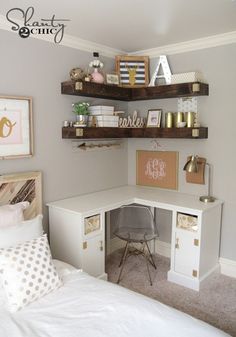 a white desk and shelves in a small room with a bed, pillows and pictures on the wall