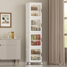 a tall white cabinet with baskets on the front and bottom shelves, in a living room