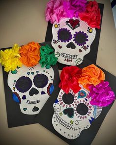 three paper plates decorated with sugar skulls and colorful flowers on top of each other,