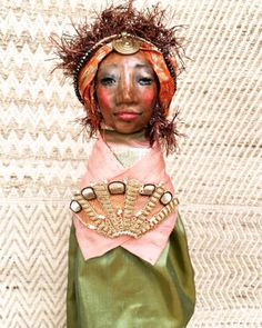 a doll is wearing a green dress and headdress