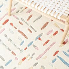 a white chair sitting on top of a floor next to a rug covered in different colored shapes