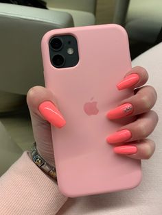 a woman's hand holding an iphone case with pink nails