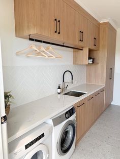 a washer and dryer in a kitchen with wooden cabinets above the counter top