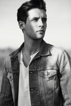 a young man in a denim jacket looks off into the distance