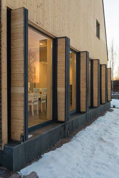 the side of a house with sliding glass doors and snow on the ground in front of it