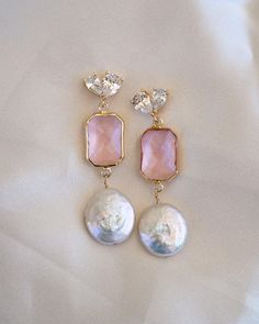 Add a touch of elegance and feminine flair to your wedding day look with our stunning Arabella Pink Drop Gold Earrings. These beautiful gold and pink drop earrings feature eye-catching freshwater coin pearls, making them a perfect choice for the boho bride who wants a pop of color to her wedding look or bridesmaid outfits! ----------------------  EARRINGS FEATURE ◊ Material: Flat Freshwater Pearls, Cubic Zirconia, Brass, Glass ◊ Dimensions/Size: 2" drop ◊ Finish: 18k Gold Plating ◊ Freshwater pearls are hand wire-wrapped with 14K gold fill wire ----------------------  PACKAGING ◊ We do the gift-wrapping for you! All jewelry comes packaged in our custom, foiled pressed gift boxes.  ---------------------- FREE US STANDARD SHIPPING on orders of $35 or more! No code required ------------------ Feminine Drop Earrings For Bridal Party, Feminine Dangle Bridal Earrings For Party, Glamorous Drop Earrings For Wedding, Feminine Bridal Earrings With Pearl Drop, Feminine Bridal Drop Earrings As Gift, Feminine Bridal Drop Earrings For Gifts, Pink Feminine Pearl Earrings For Wedding, Elegant Linear Drop Earrings For Wedding, Pink Teardrop Pearl Earrings For Wedding