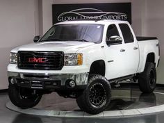 a white truck is on display in a showroom with black tires and rims