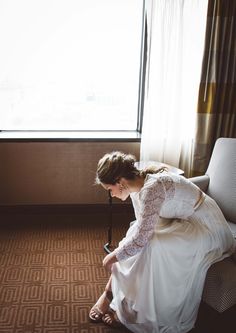 a woman kneeling down in front of a window next to a chair with her feet on the ground