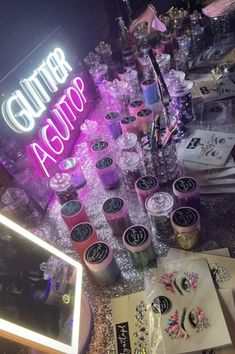 an assortment of nail polish and glitters on display in front of a neon sign