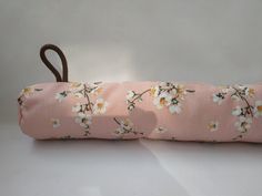 a pink flowered umbrella with brown handle on a white tablecloth covered surface, ready to be used as a decorative item