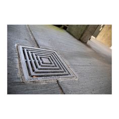 a manhole cover on the side of a road with a square hole in it