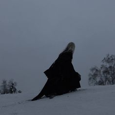 a woman sitting on top of a snow covered slope