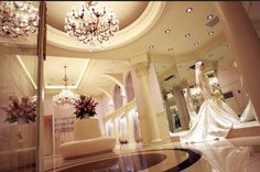 a bride's dress is on display in the lobby at a wedding venue with chandeliers hanging from the ceiling