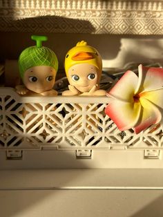 two little dolls are sitting in the window sill with their heads turned to look like they're having fun