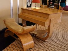 a wooden piano sitting on top of a hard wood floor next to a woman in a black dress