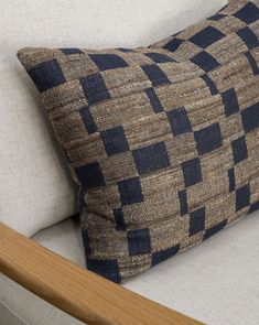 a close up of a pillow on a couch with a wood frame and back rest