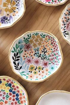 colorful plates with flowers painted on them sitting on a wooden table next to each other