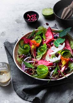 a bowl filled with watermelon, radishes and other vegetables on top of a table