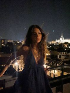 a woman standing on top of a roof at night