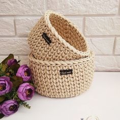 two baskets sitting next to each other on a table with flowers in front of them