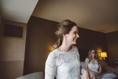 two women sitting on a bed laughing and looking at each other in the same room