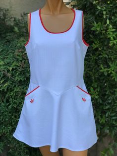 Here is vintage white polyester tennis dress. Made By Adidas.No size tag .Following are the measurements. Bust 36",waist 31",Hips 46",length measured from top of shoulder to bottom 32".Made out of a solid white textured polyester fabric.Zips up the back.Has two front side pockets.Red piping around neck, arms, and pockets.In very nice vintage condition. Please take special note of measurements. 1970s sizing was very small compared todays standards.So Please take note of length.Please e mail me if Vintage Tennis, Womens Sports, Dress Out, Adidas White, Great Lengths, White Texture, Tennis Dress, White Adidas, How To Look Pretty