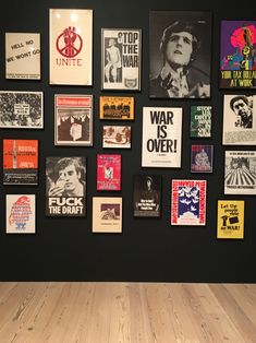 a wall with many posters on it and a wooden floor in front of the wall