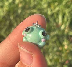 a tiny toy frog is sitting on someone's finger