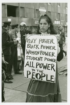 a woman holding a sign that says gay power, black power, women power, student power, all power to the people