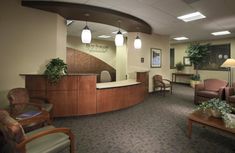 an office lobby with chairs, desks and plants on the counter in front of it