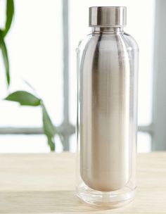 a glass bottle sitting on top of a wooden table next to a green leafy plant