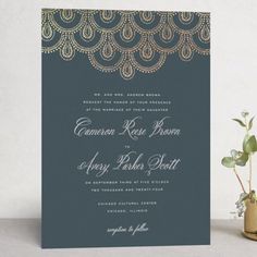 a wedding card with an intricate design on the front and back, sitting next to a potted plant