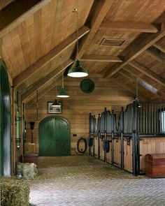 the inside of a building with horses in stalls and hay bales on the floor