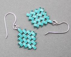 a pair of earrings with turquoise beads and silver earwires on a gray surface