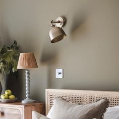 a bed room with a neatly made bed and two lamps on the wall above it