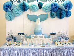 a table topped with blue and white desserts next to an ocean themed wallpaper