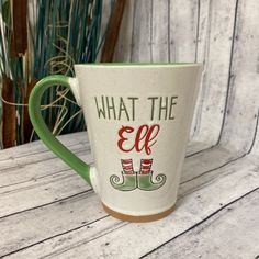 a green and white coffee cup with the words what the elf is wearing on it