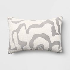 a gray and white pillow with wavy lines on the front, sitting against a grey wall