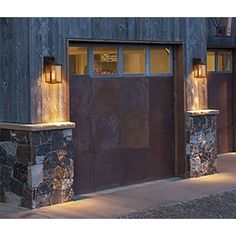 two garage doors are lit up at night in front of a building with stone pillars