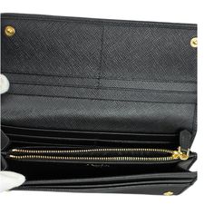 Immerse yourself in luxury with the Prada Nylon Long Flap Wallet in Black. Made from premium nylon and adorned with an iconic gold Prada logo plaque, this wallet exudes sophistication. Its spacious interior, crafted in beautiful black saffiano leather, provides ample space to conveniently store your cash, cards, and other essentials. With a practical size of approximately 7.5 inches long and 4 inches high, this wallet is perfect for everyday use. Its secure closure, featuring a snap button, keep Elegant Bifold Wallet With Gold-tone Logo Plaque, Luxury Business Wallets With Gold-tone Logo Plaque, Luxury Business Wallet With Gold-tone Logo, Designer Black Saffiano Leather Wallets, Luxury Travel Wallets With Gold-tone Hardware, Luxury Saffiano Leather Rectangular Wallet, Luxury Saffiano Leather Wallet For Evening, Luxury Saffiano Leather Wallets For Everyday Use, Luxury Saffiano Leather Wallet