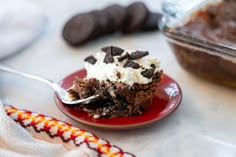 a piece of cake on a red plate with a spoon in it and some cookies