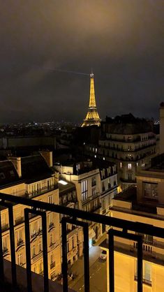 the eiffel tower is lit up at night from an apartment balcony in paris