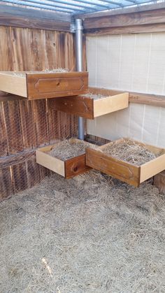 two wooden boxes filled with hay next to a fenced in area that has wood slats on it