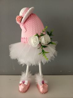 a stuffed animal wearing a pink hat and white tutu with flowers on it's head